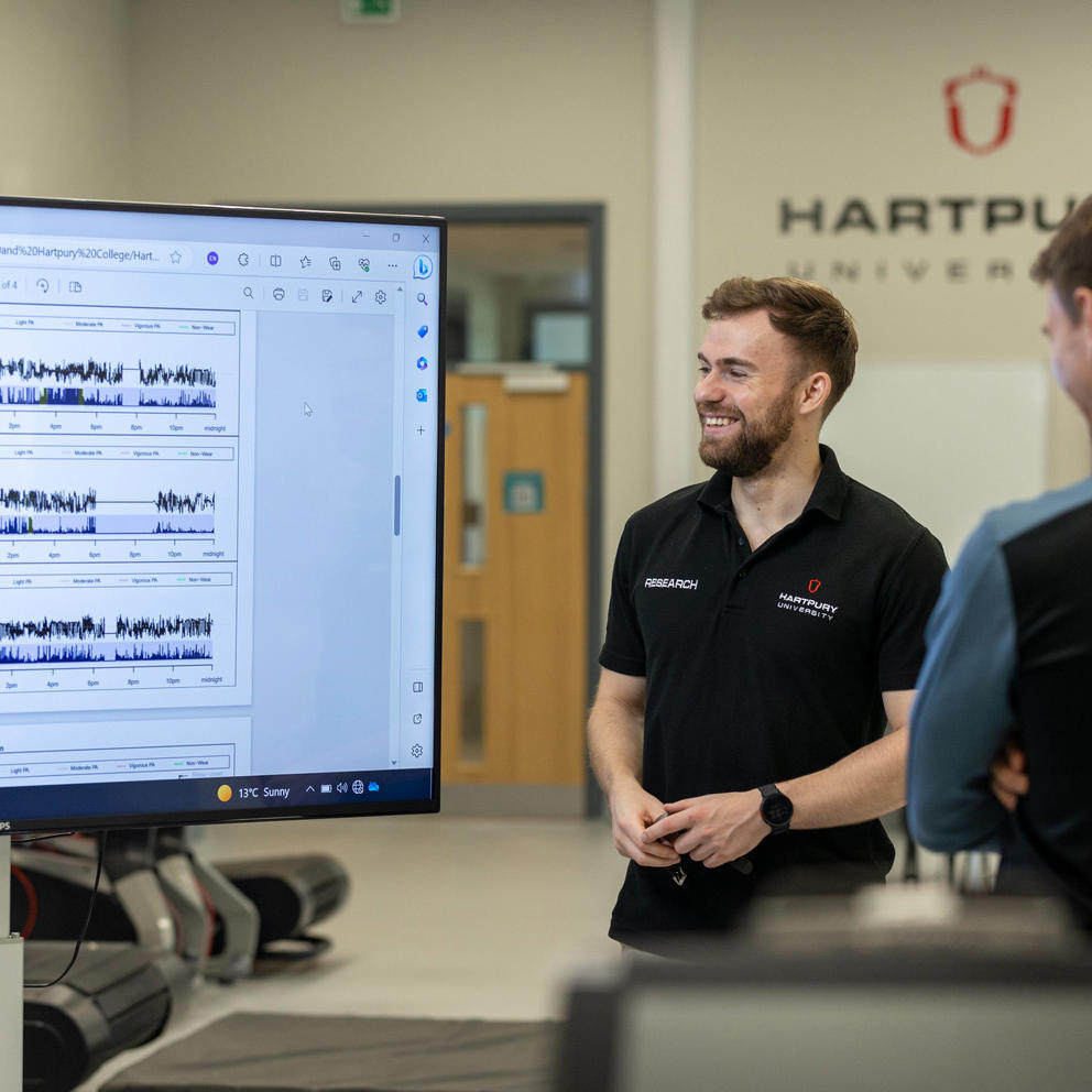 Two university research students in a sports lab looking at a screen displaying readings