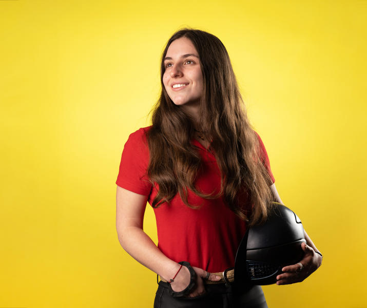 Image of international student at Hartpury holding helmet and smiling for a candid photograph