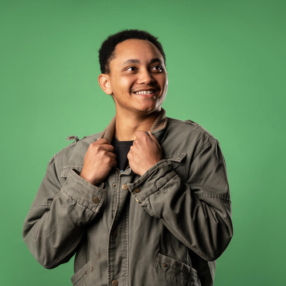 Image of international student smiling to their left whilst holding the collar of their jacket
