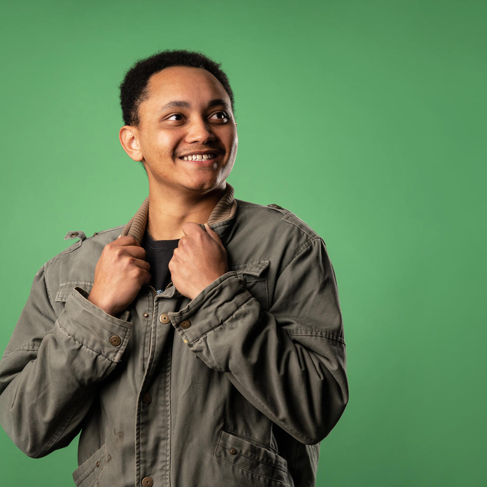 Image of international student smiling to their left whilst holding the collar of their jacket